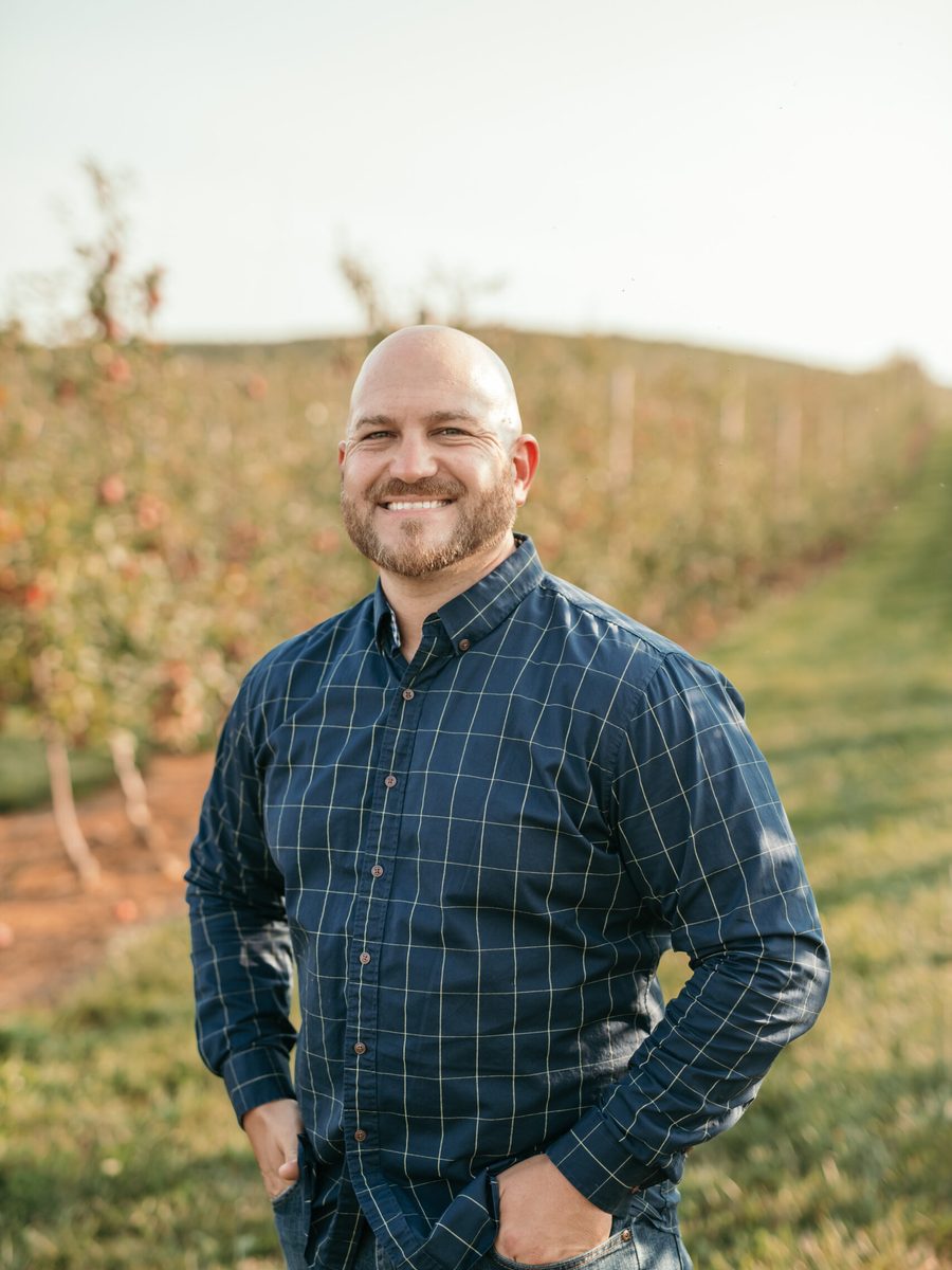Andrew Fultz, team lead, standing in an apple orchard